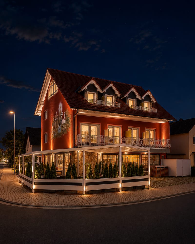 Das Hotel Weinhaus Wiedemann am Abend: beleuchtete Fassade mit Wandbild und Terrasse
